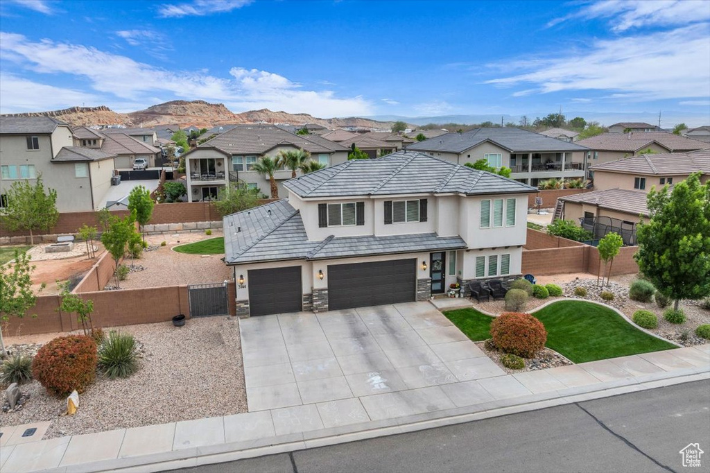 Traditional-style house with a gate, a residential view, a garage, stucco siding, and fence private yard