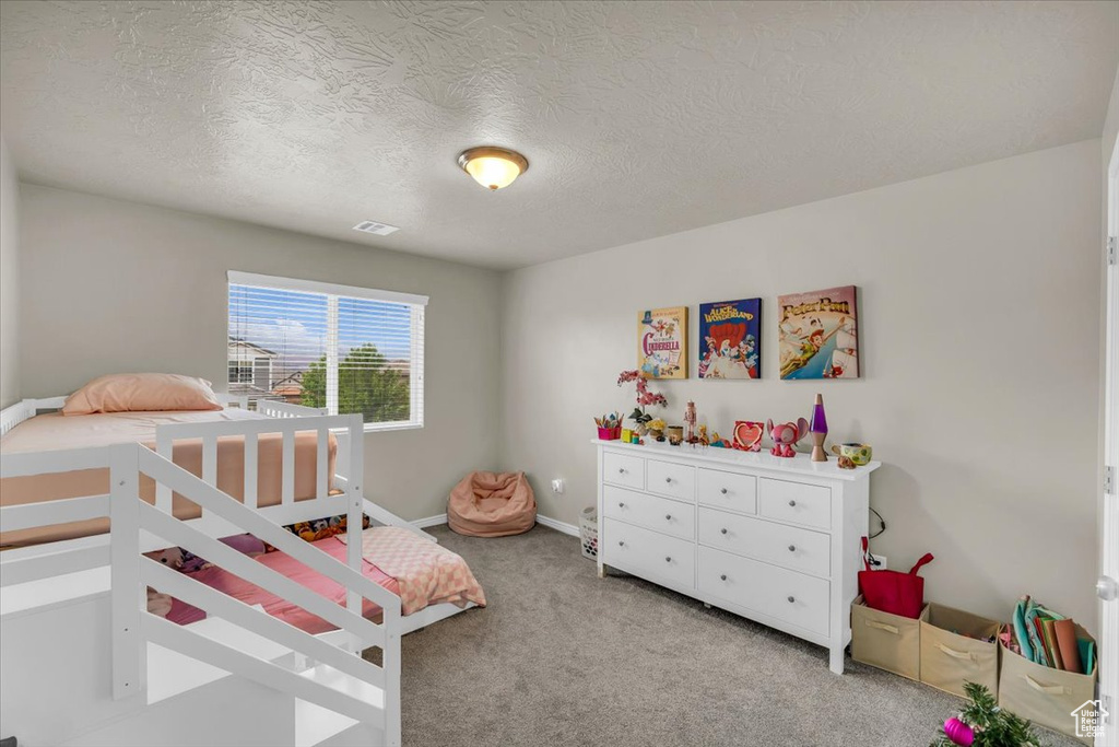 Carpeted bedroom featuring a textured ceiling, baseboards, and visible vents