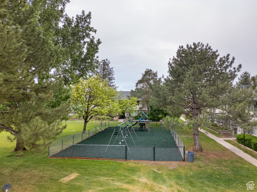 View of community featuring fence, playground community, and a lawn