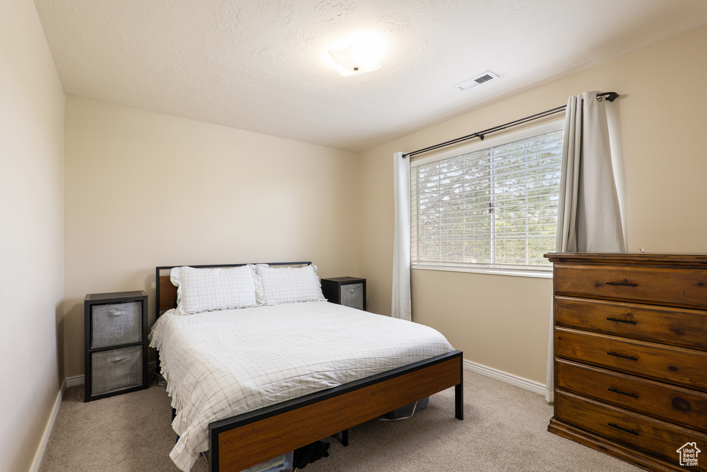 Bedroom featuring light carpet, baseboards, and visible vents