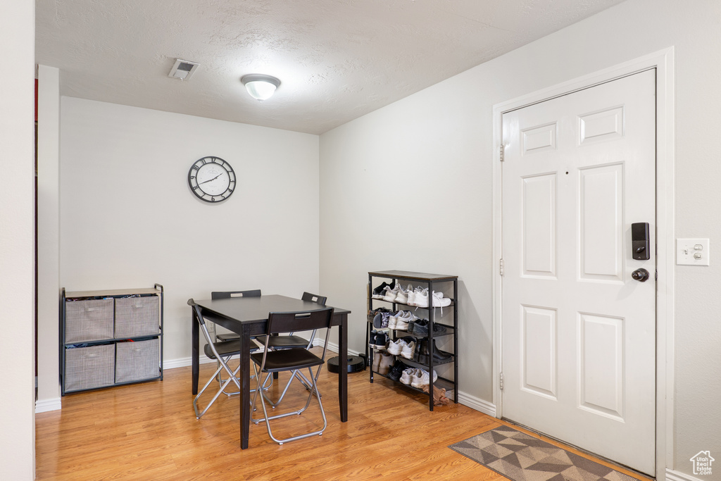Dining space featuring baseboards, light wood-style floors, visible vents, and a textured ceiling