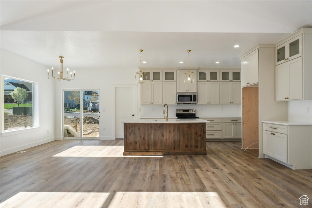 Kitchen with light wood finished floors, stainless steel appliances, light countertops, a chandelier, and recessed lighting