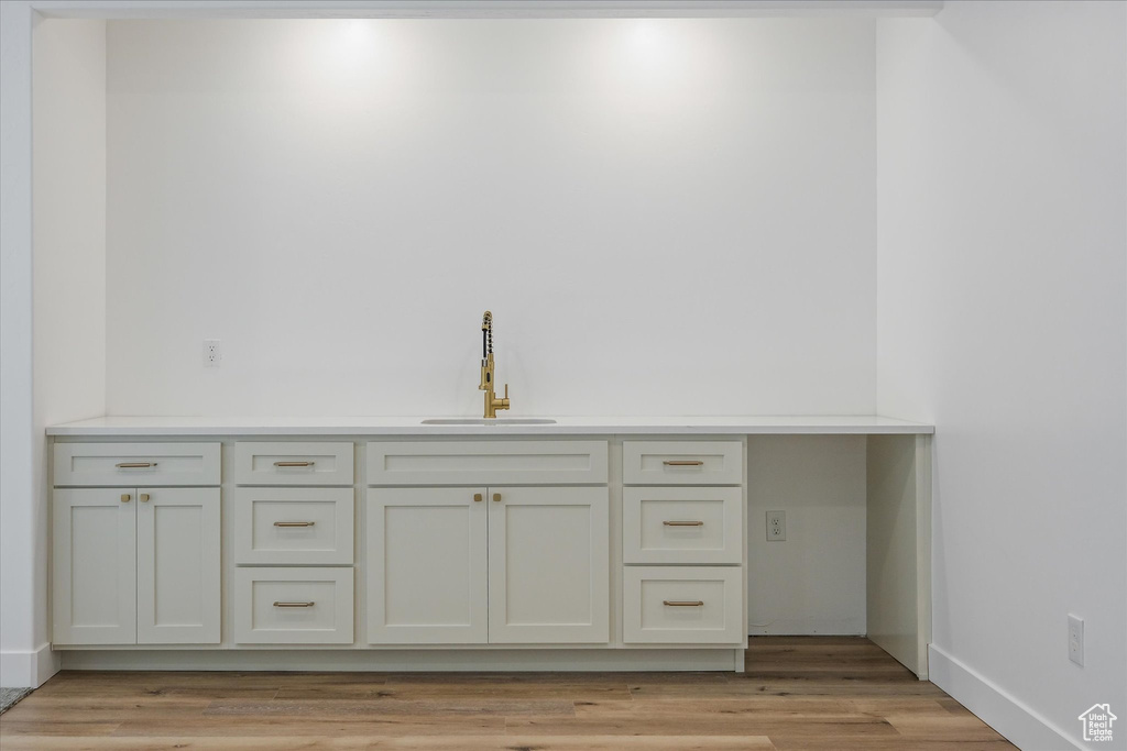Bar featuring light wood-type flooring, baseboards, and a sink