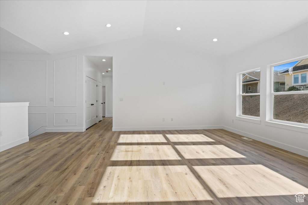 Spare room with baseboards, wood finished floors, recessed lighting, and vaulted ceiling