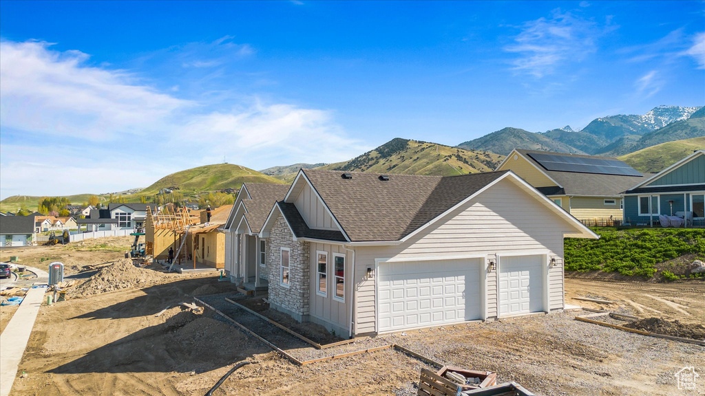 View of front of house featuring an attached garage, a mountain view, driveway, and a shingled roof