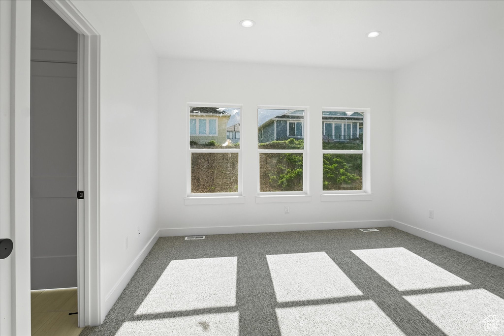 Unfurnished room featuring carpet floors, baseboards, visible vents, and recessed lighting