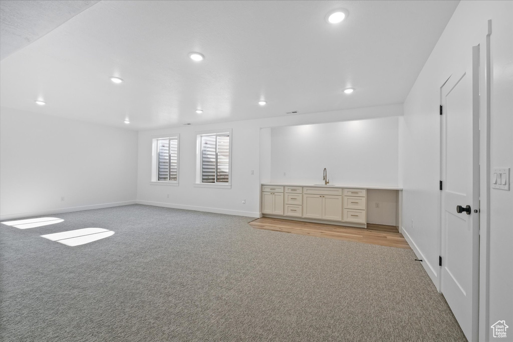 Unfurnished room with light carpet, baseboards, a sink, and recessed lighting