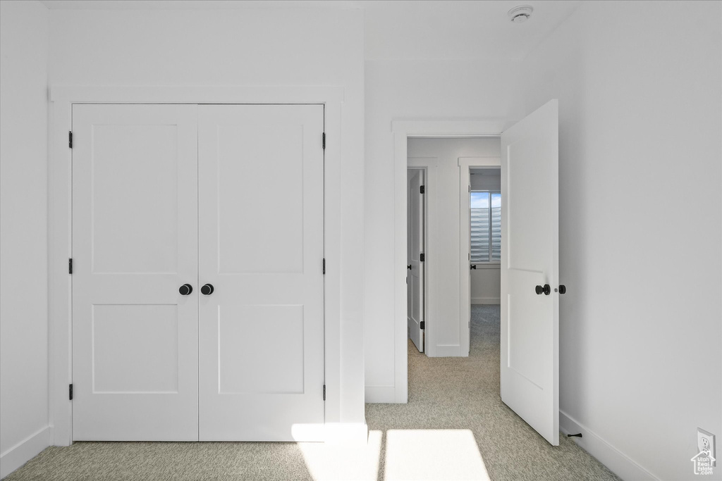 Unfurnished bedroom with light colored carpet, a closet, and baseboards
