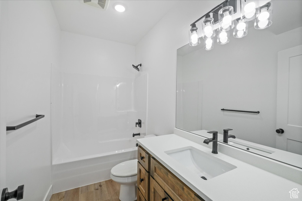 Bathroom featuring toilet,  shower combination, vanity, and wood finished floors