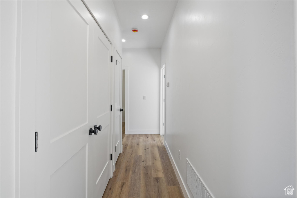 Hall featuring light wood-style floors, baseboards, and recessed lighting