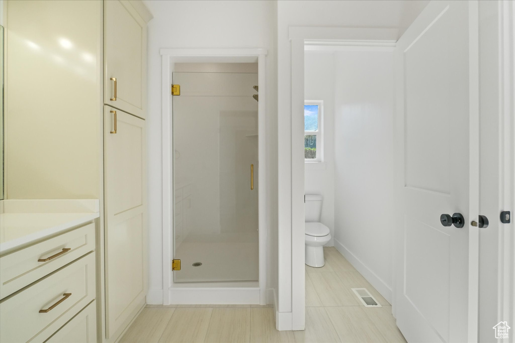 Bathroom with toilet, vanity, visible vents, a shower stall, and baseboards