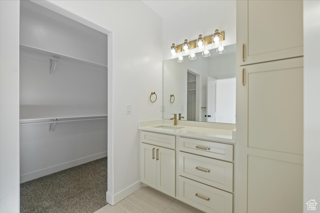 Full bathroom with baseboards, vanity, and a walk in closet
