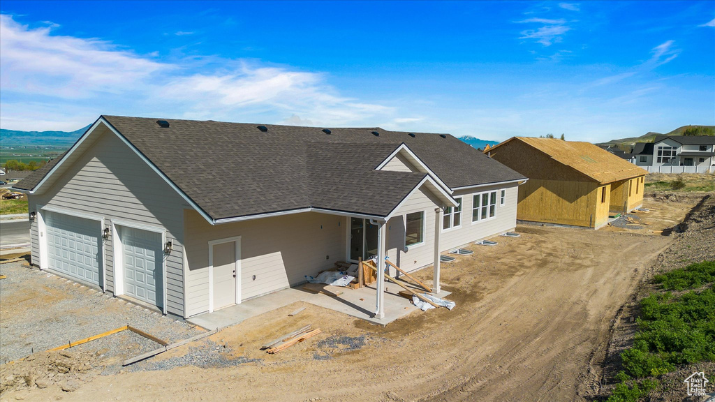 Rear view of house featuring driveway and roof with shingles
