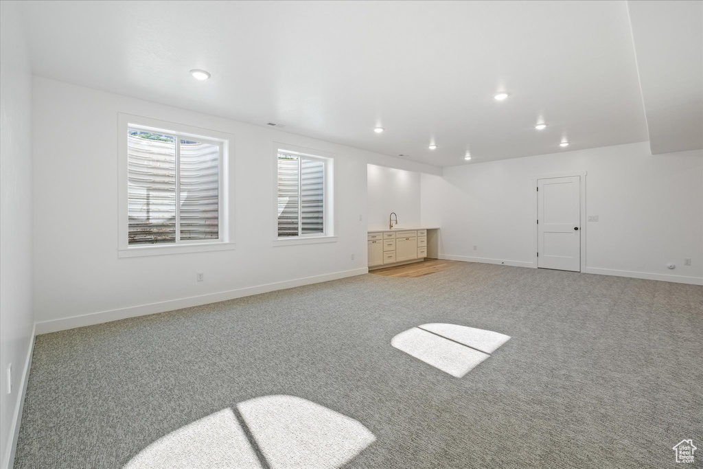 Interior space with recessed lighting, light carpet, baseboards, and a sink