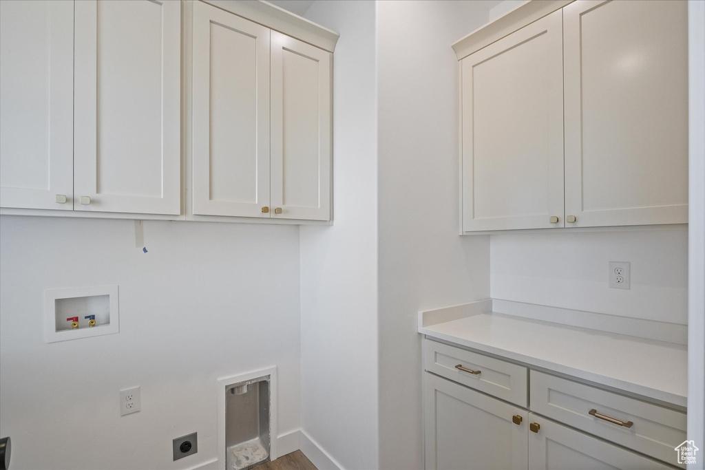 Laundry area featuring wood finished floors, electric dryer hookup, cabinet space, washer hookup, and baseboards