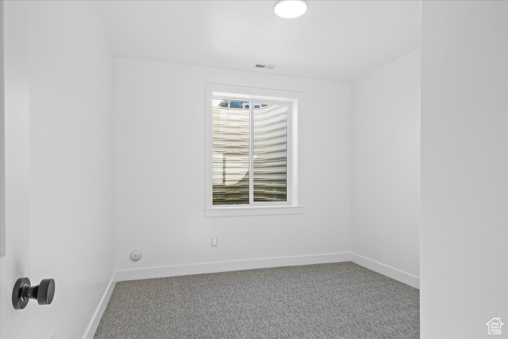 Empty room featuring carpet, visible vents, and baseboards
