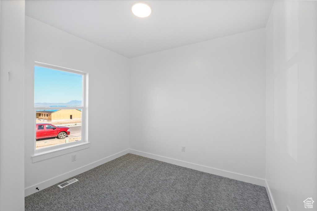 Carpeted empty room featuring visible vents and baseboards