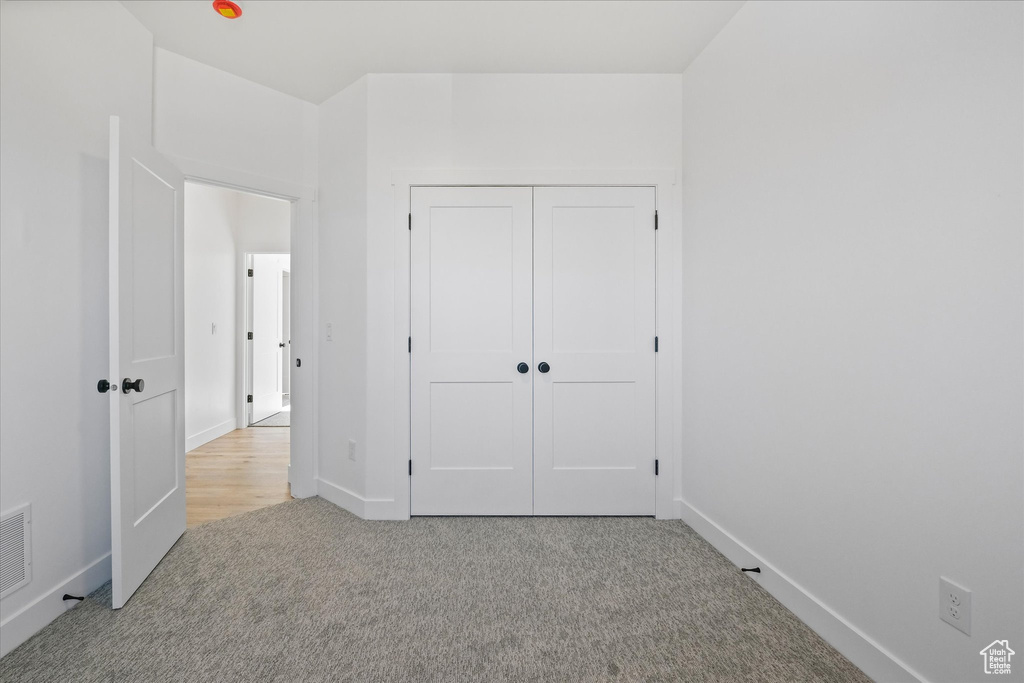Unfurnished bedroom with carpet, a closet, and baseboards