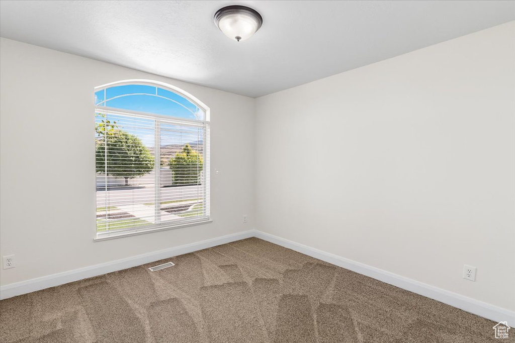 Carpeted empty room featuring baseboards and visible vents