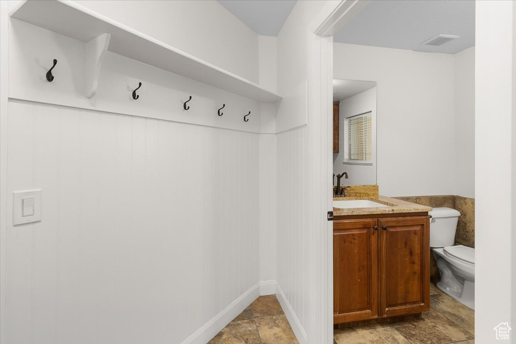 Mudroom with a sink, a wainscoted wall, stone finish flooring, and visible vents