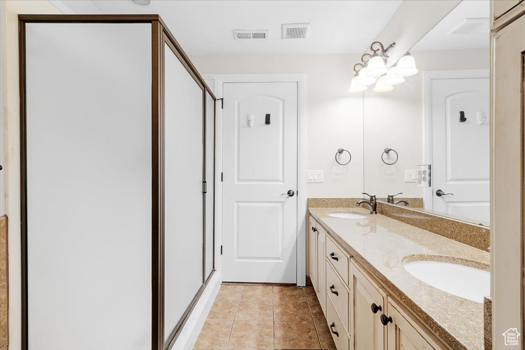 Bathroom featuring double vanity, visible vents, a shower stall, and a sink