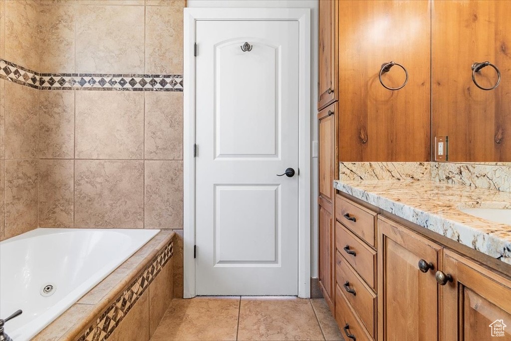 Bathroom featuring tile patterned floors, a tub with jets, and vanity
