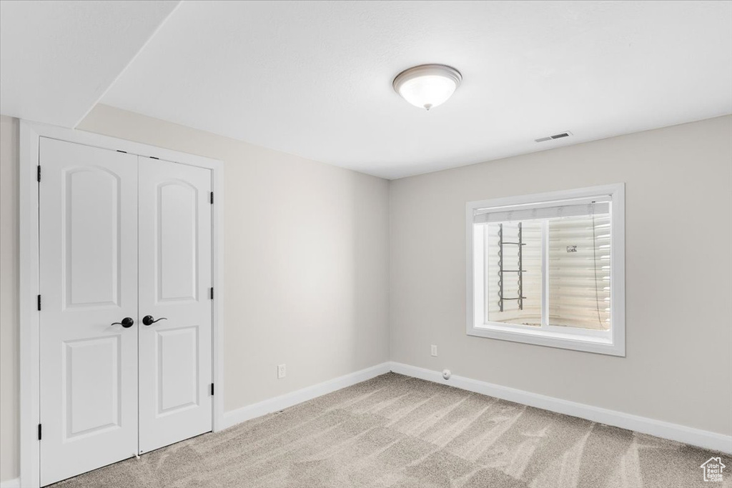 Empty room with light carpet, baseboards, and visible vents