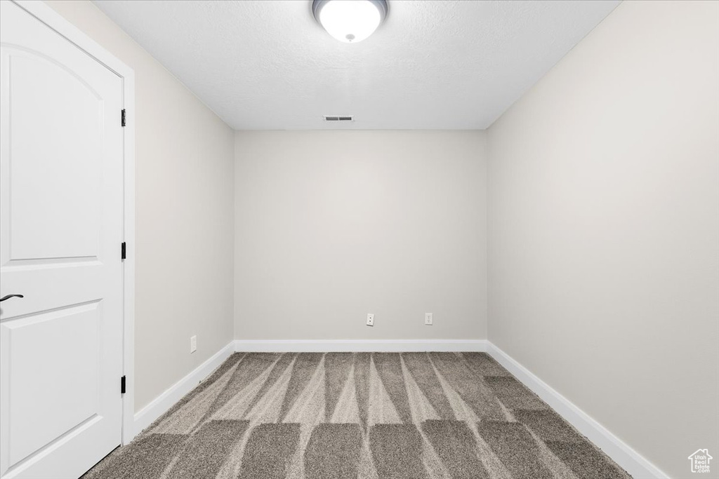 Unfurnished room featuring baseboards, visible vents, and light colored carpet