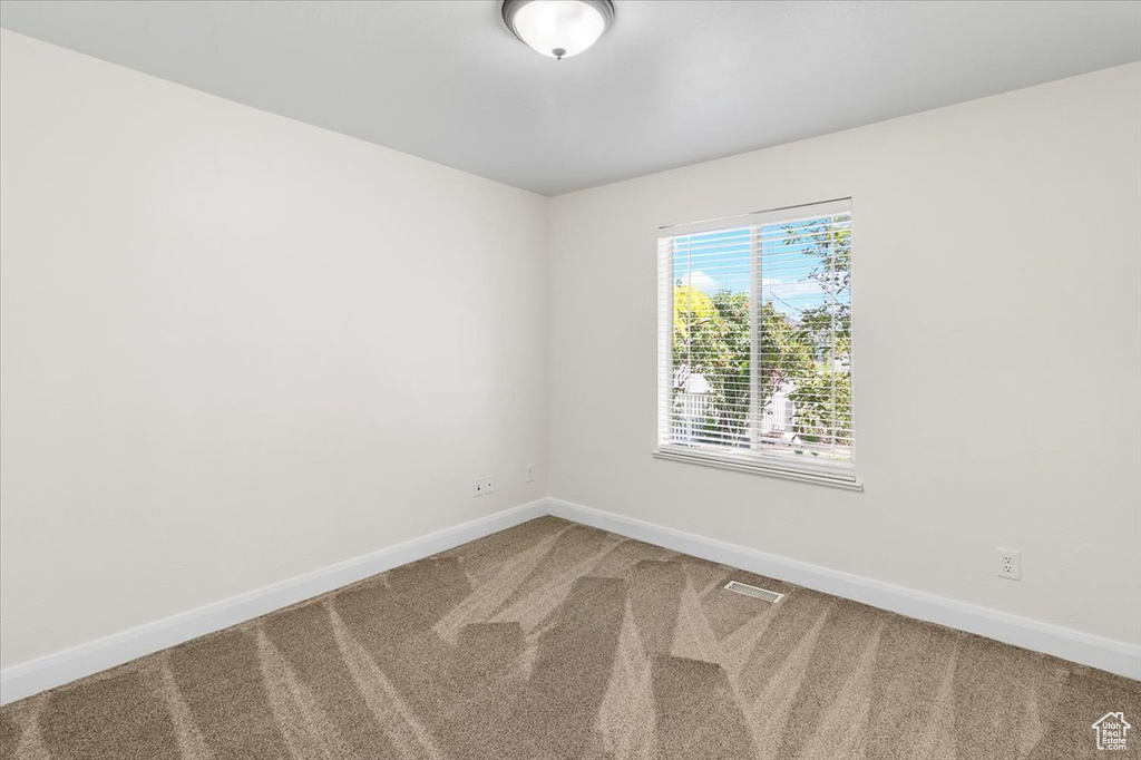 Carpeted spare room with visible vents and baseboards