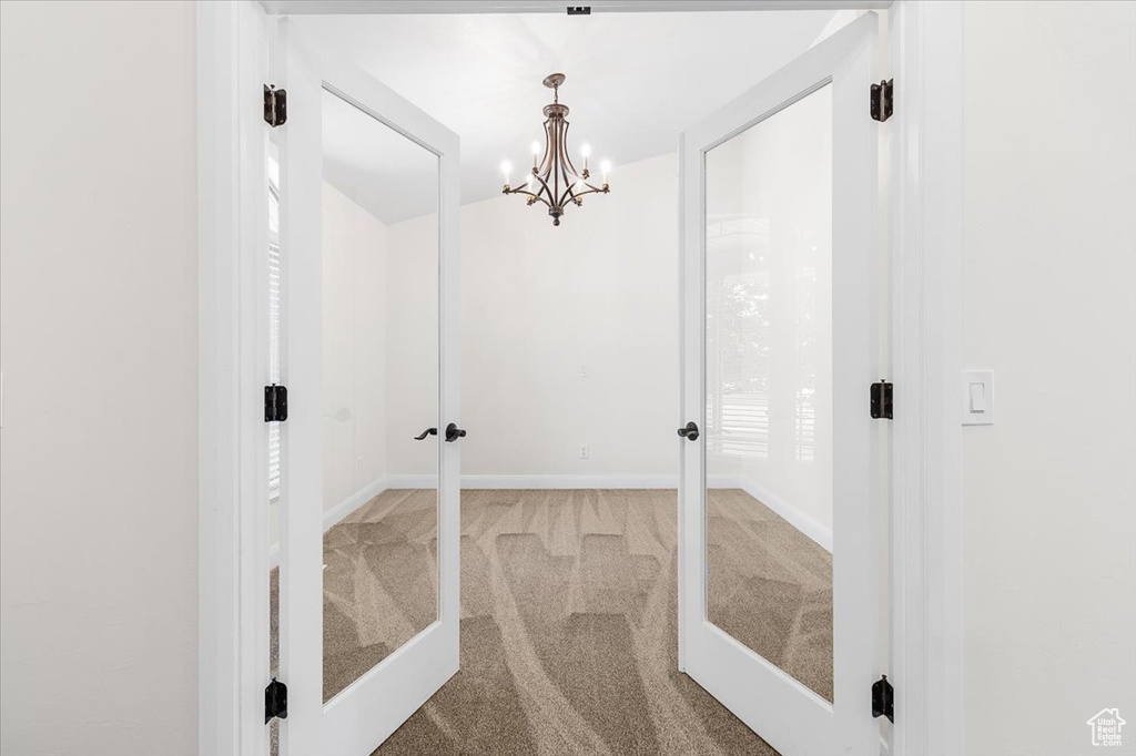 Hallway featuring baseboards, carpet flooring, and an inviting chandelier