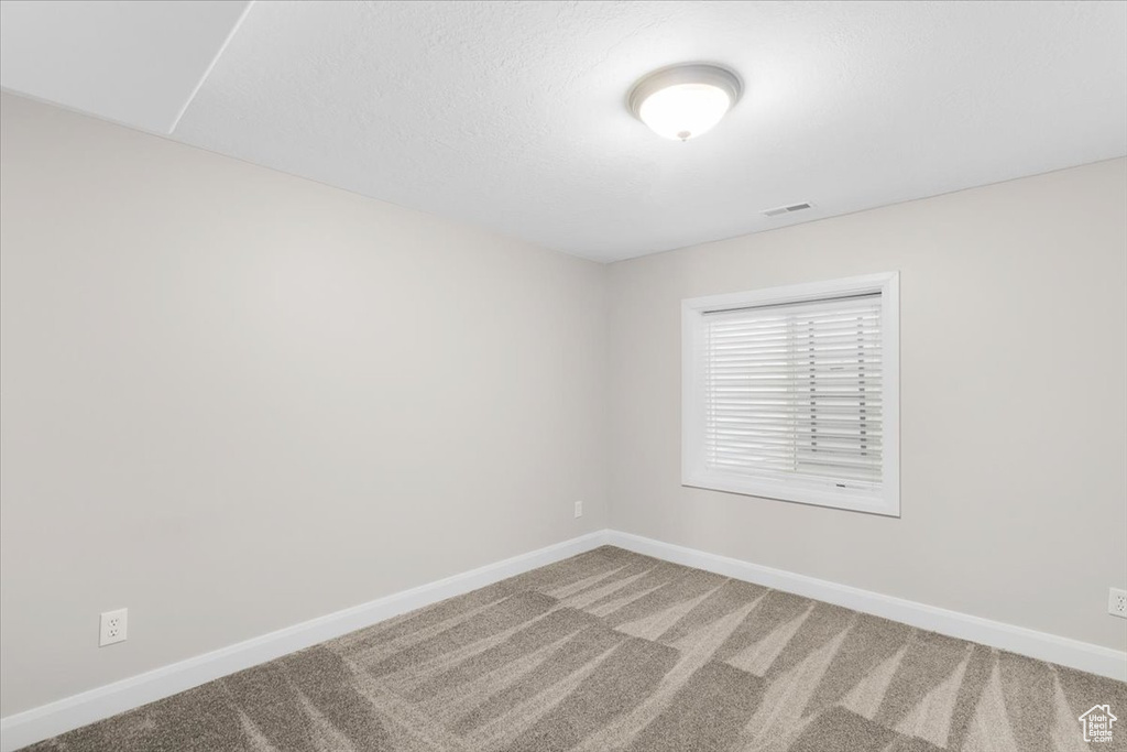 Empty room with carpet, visible vents, and baseboards