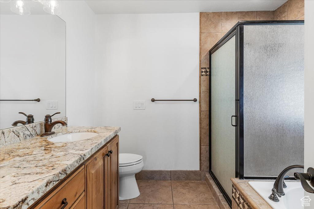 Bathroom featuring tile patterned floors, vanity, toilet, and a stall shower