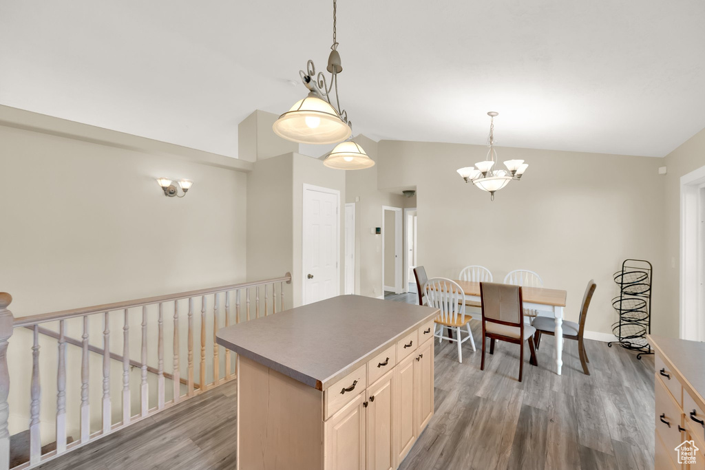 Kitchen featuring lofted ceiling, light wood finished floors, an inviting chandelier, a center island, and baseboards