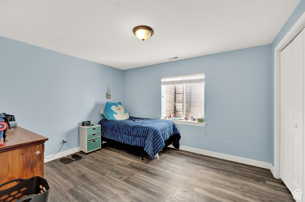 Bedroom with baseboards, a closet, visible vents, and wood finished floors