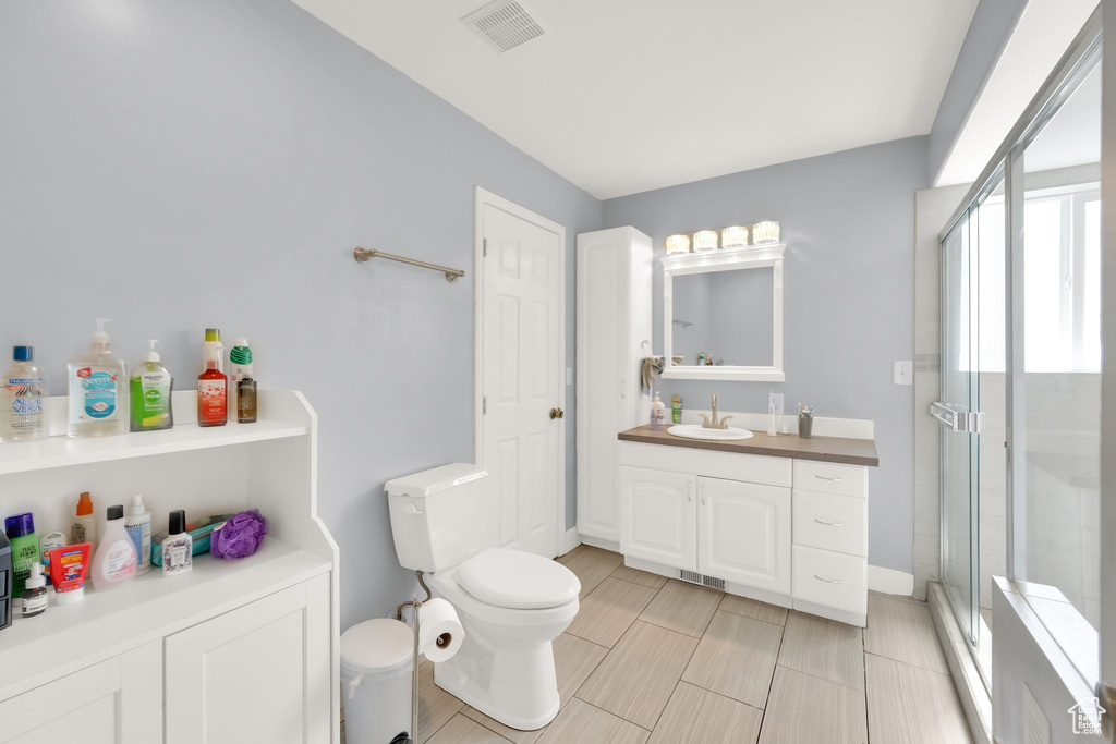 Bathroom with toilet, vanity, visible vents, and a stall shower