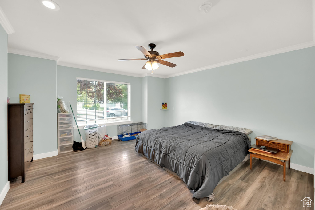 Bedroom with baseboards, ornamental molding, and wood finished floors