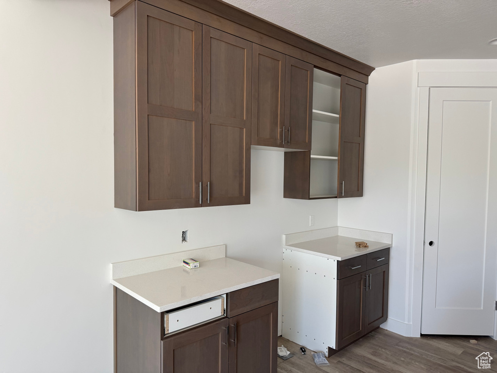 Kitchen featuring light wood-style floors, light countertops, and dark brown cabinets