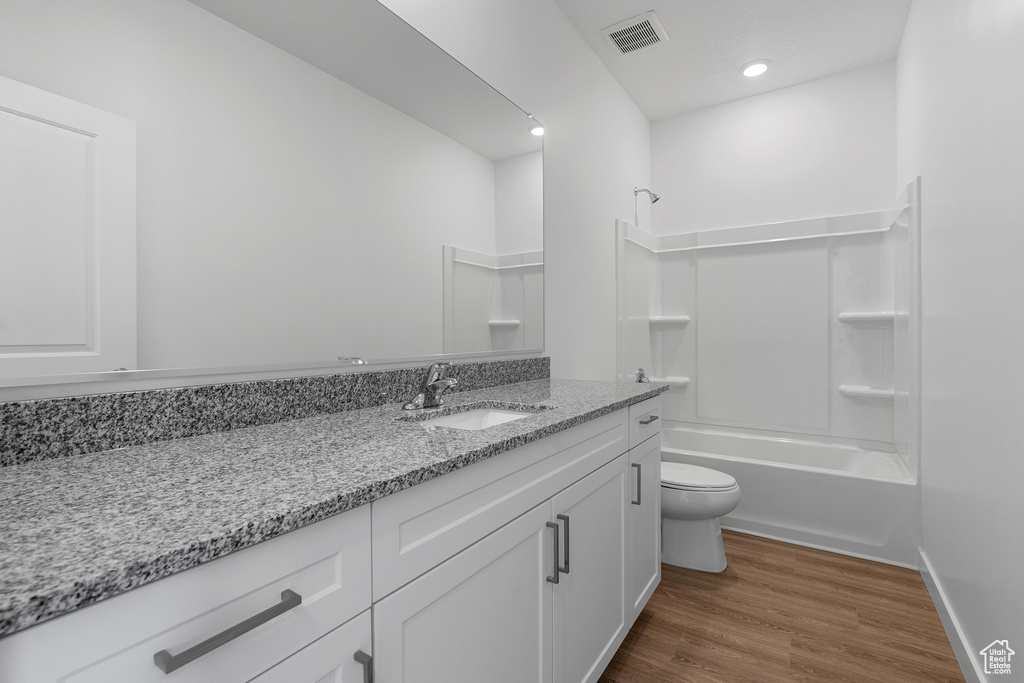 Full bath with toilet, wood finished floors, shower / tub combination, visible vents, and vanity