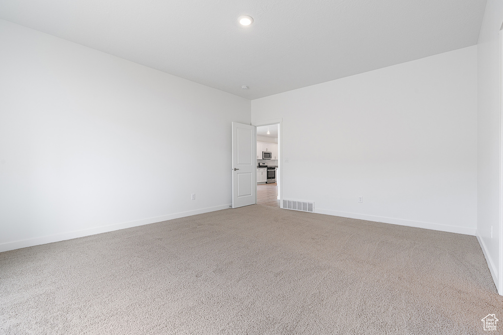 Empty room featuring light colored carpet, visible vents, baseboards, and recessed lighting