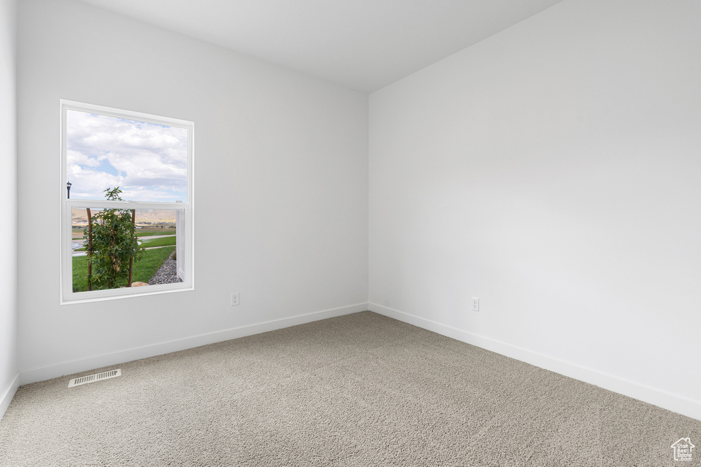 Carpeted empty room featuring visible vents and baseboards