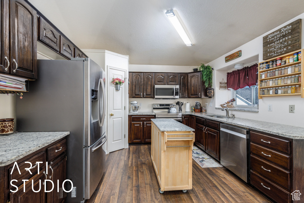 Kitchen featuring dark brown cabinets, a sink, dark wood finished floors, appliances with stainless steel finishes, and a kitchen island