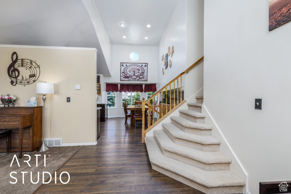 Entryway with recessed lighting, baseboards, wood finished floors, stairway, and a high ceiling