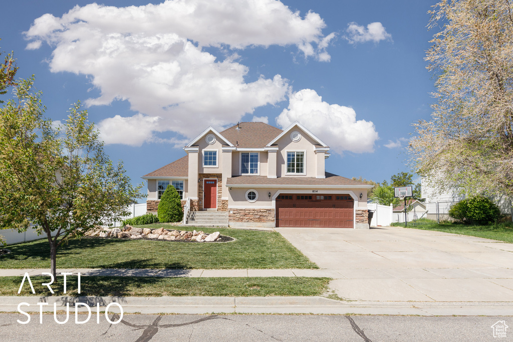 View of front facade featuring fence, an attached garage, driveway, stucco siding, and a front yard