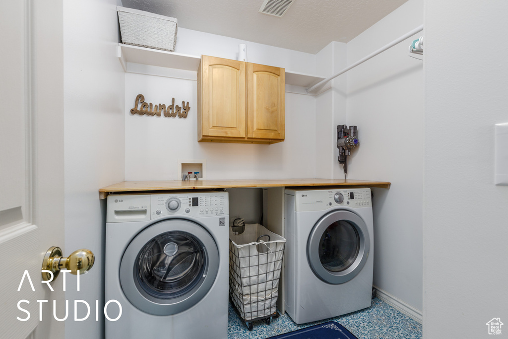 Laundry area with baseboards, independent washer and dryer, visible vents, and cabinet space