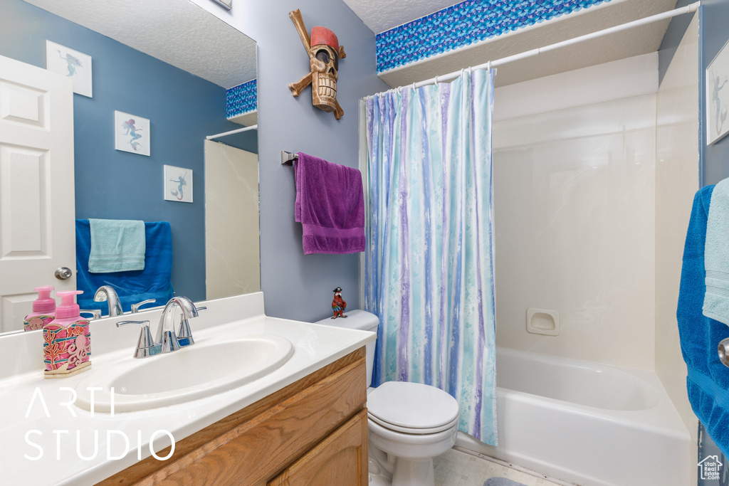 Bathroom with vanity, toilet, a textured ceiling, and shower / bath combination with curtain