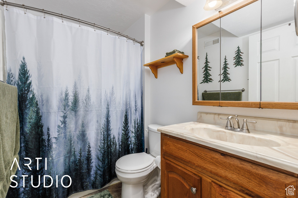 Bathroom featuring vanity, toilet, a shower with curtain, and visible vents