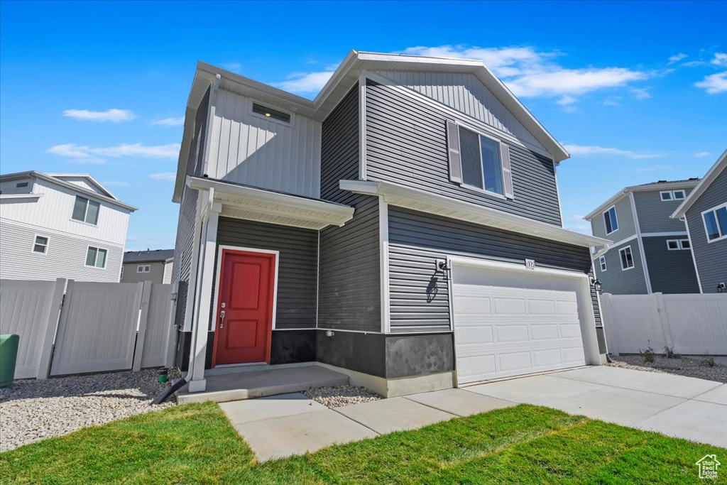 View of front facade featuring concrete driveway, board and batten siding, an attached garage, and fence