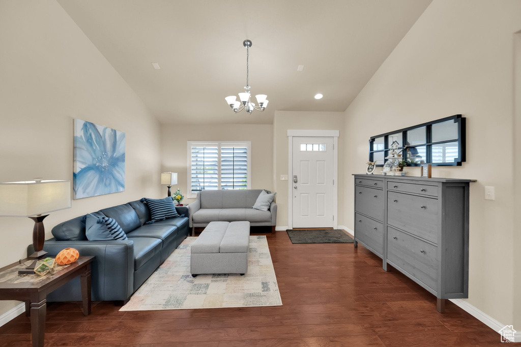 Living area with a chandelier, dark wood-style flooring, baseboards, and high vaulted ceiling