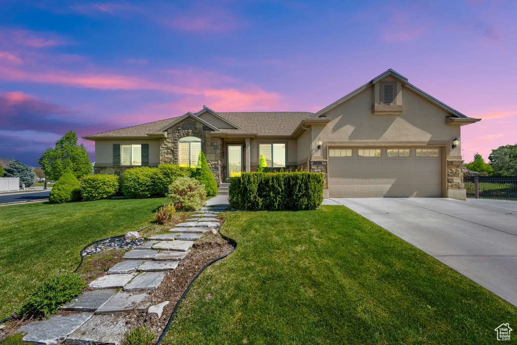 Single story home featuring concrete driveway, stucco siding, stone siding, and a front yard
