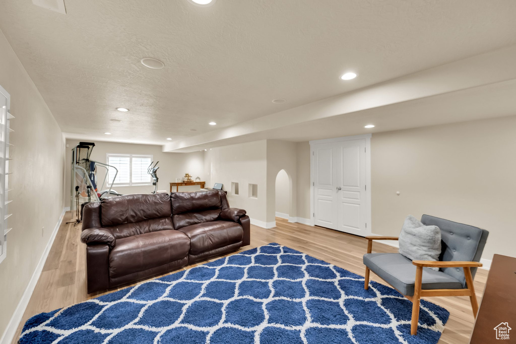 Living room featuring light wood-style flooring, baseboards, arched walkways, and recessed lighting